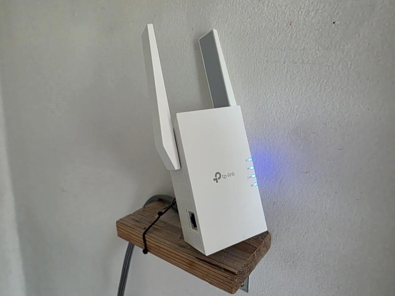 TP-Link Wi-Fi extender installed on a small wall shelf