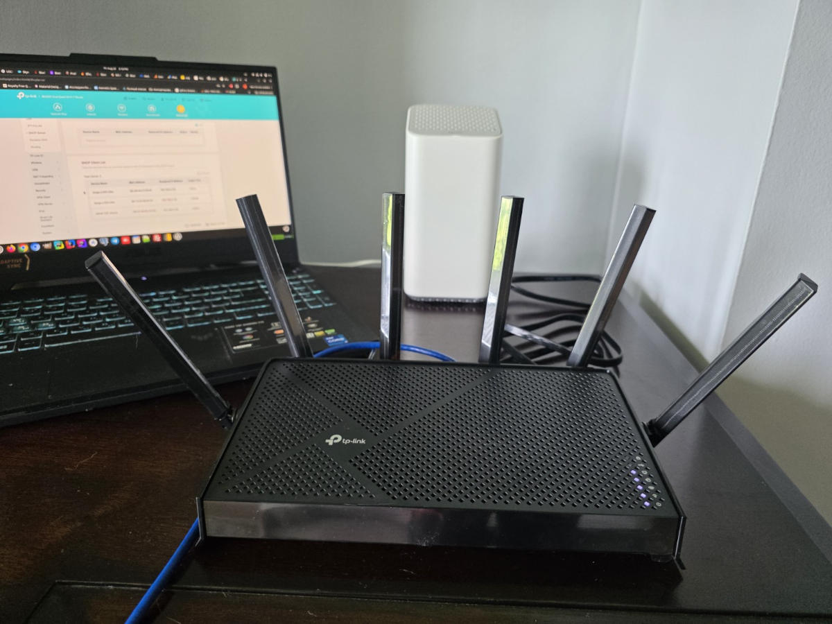 TP-Link router connected beside a laptop and internet gateway during setup